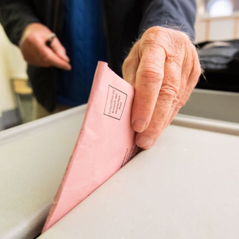 Mann wirft seinen Wahlumschlag in eine Urne (Foto: picture-alliance / Reportdienste, picture alliance/dpa | Julian Stratenschulte)