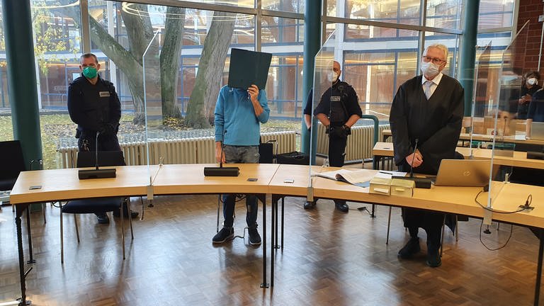 Angeklagter steht vor Landgericht Konstanz und verdeckt Gesicht mit Mappe (Foto: SWR, Friederike Fiehler)