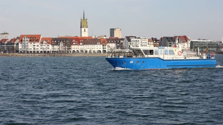Ein Boot der Wasserschutzpolizei auf dem Bodensee, im Hintergrund die Stadt Friedrichshafen (Archivbild)
