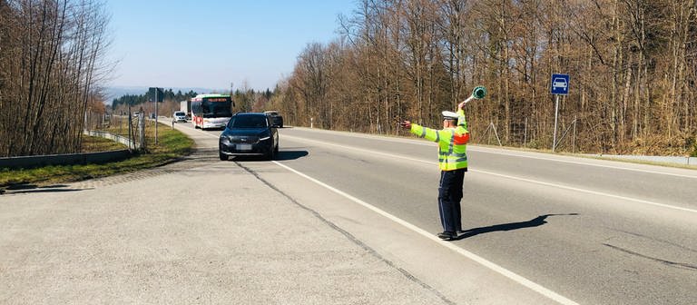 Polizist winkt mit Stop-Kelle Autofahrer von der Straße (Foto: SWR, Moritz Kluthe)