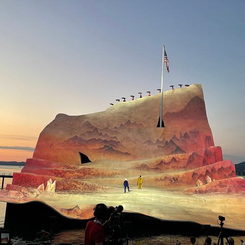 Wie in Abendsonne getaucht wirkt das Bühnenbild. Aus dem Blatt Papier ragt ein Fahnenmast mit der amerikanischen Flagge bei Madame Butterfly bei den Bregenzer Festspielen 2022 (Foto: SWR, Karin Wehrheim)