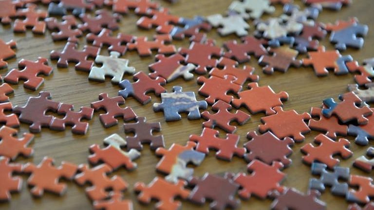 Puzzleteile liegen bunt durcheinander auf einer hölzernen Oberfläche