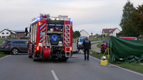 Ein Polizist steht neben einem Feuerwehrfahrzeug an der Unfallstelle auf der Bundesstraße 312 bei Erlenmoos.  (Foto: dpa Bildfunk, picture alliance/dpa/TNN, David Pichler)