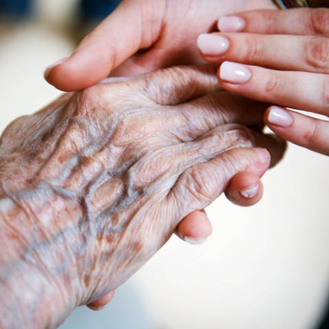 Die Hand einer jungen Frau hält die Hand einer älteren Frau. (Symbolbild) (Foto: dpa Bildfunk, picture alliance/dpa/Christophe Gateau (Symbolbild))
