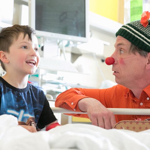 Ein Junge mit einem Klinikclown in einem Krankenhauszimmer (Foto: Pressestelle, Dachverband Clowns in Medizin und Pflege Deutschland e.V./Nadine Hennig)
