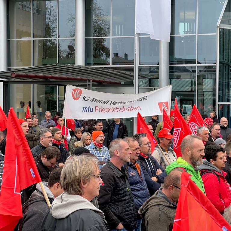 Menschen stehen in Friedrichshafen und streiken. Einige haben Fahnen der IG Metall dabei. (Foto: SWR, Martina Meisenberg)