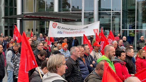 Menschen stehen in Friedrichshafen und streiken. Einige haben Fahnen der IG Metall dabei. (Foto: SWR, Martina Meisenberg)