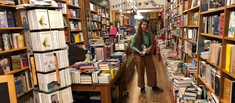 Anna Rahm steht in ihrer Bücherei vor Regalen voller Bücher. (Foto: SWR, Thea Thomiczek)