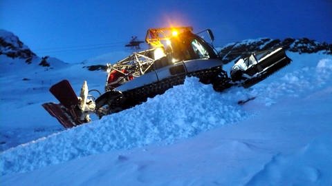 Eine Pistenraupe im Abendlicht auf einem Berghang. Eine Pistenraupe wie diese hat zwei Skifahrer am Arlberg überfahren. (Foto: dpa Bildfunk, picture-alliance/Michael Donhauser (Symbolbild))
