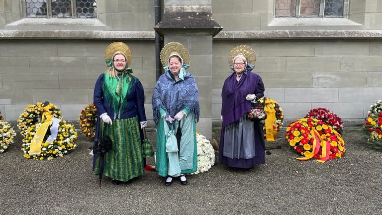 Drei Frauen einer Trachtengruppe, die zur Trauerfeier nach Salem gekommen sind, im Hintergrund zahlreiche Trauerkränze. (Foto: SWR, Julia Kretschmer)