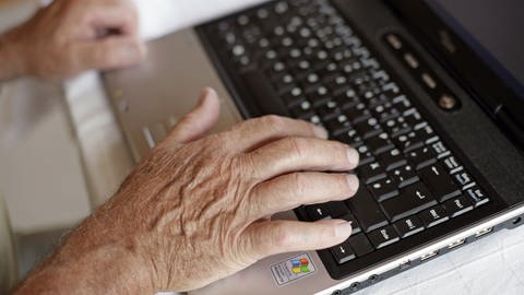 Die Hand eines älteres Mannes tippt auf der Tastatur eines Laptops.  (Foto: dpa Bildfunk, picture alliance/dpa/Andreas Gebert (Symbolbild))