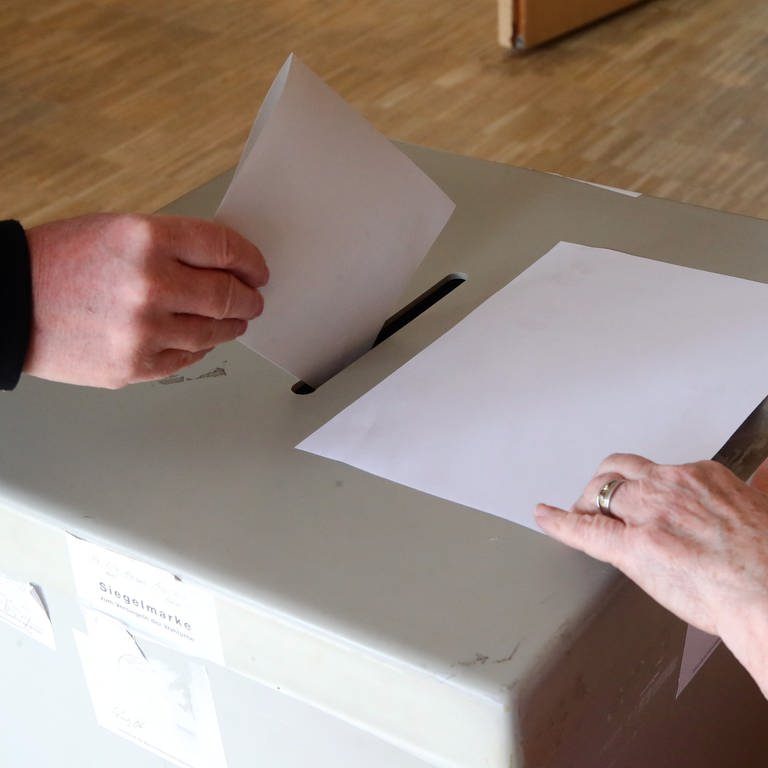 Eine Hand wirft einen Stimmzettel in eine Wahlurne. (Foto: picture-alliance / Reportdienste, Picture Alliance)
