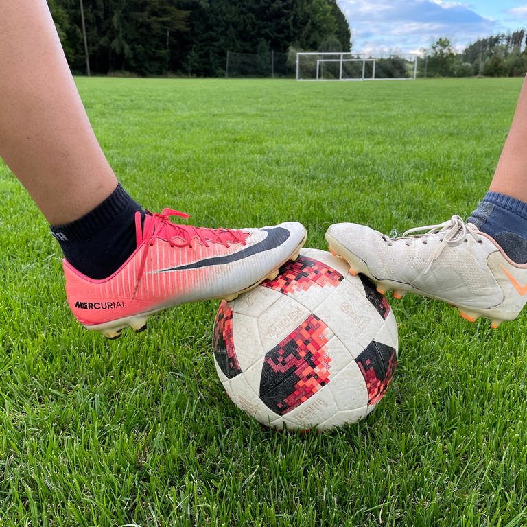 Die Füße zweier Fußballspielerinnen auf einem Ball. (Foto: SWR, Corinna Scheller)