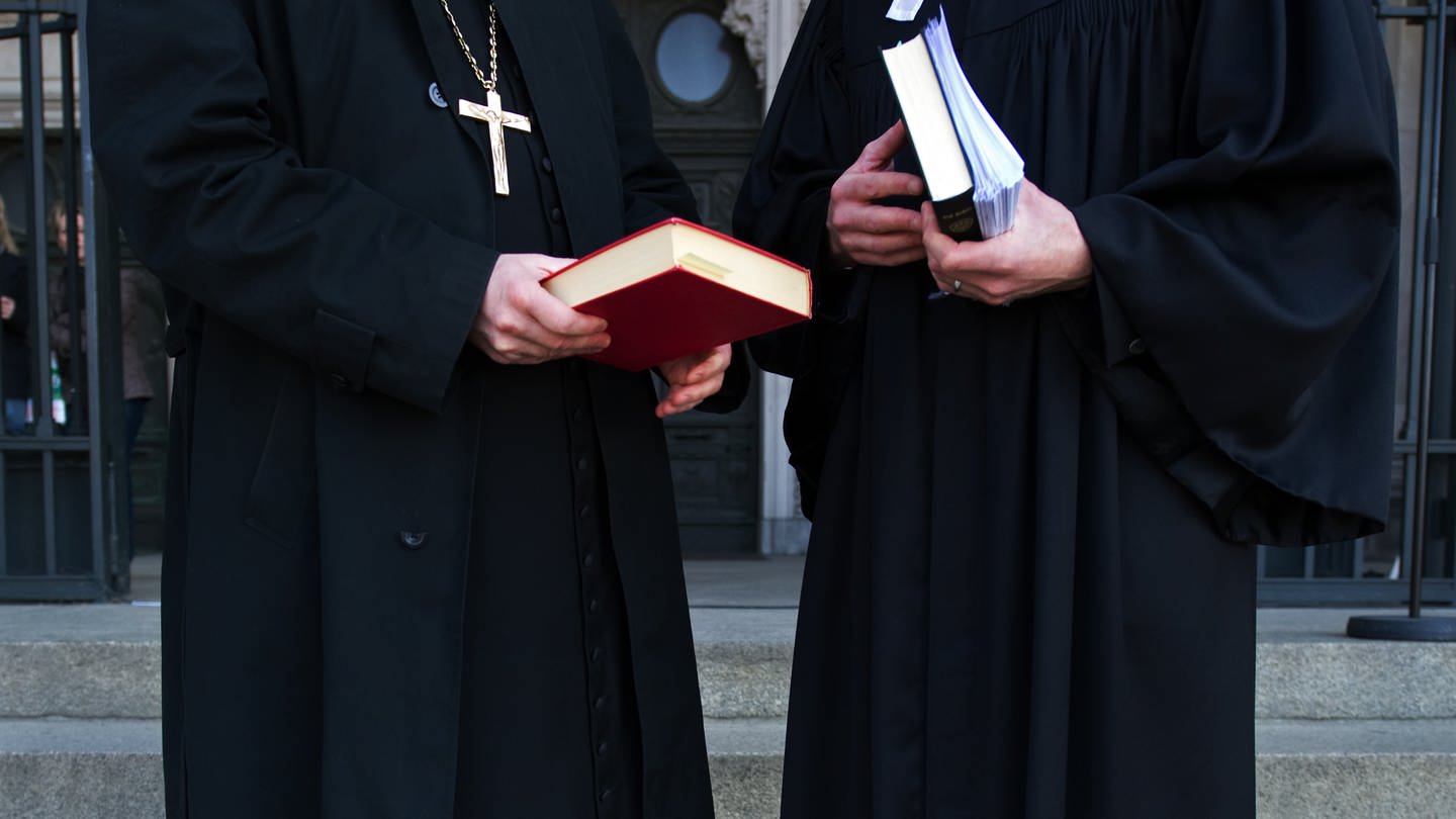 Zwei Geistliche unterhalten sich und halten eine Bibel in den Händen (Foto: picture-alliance / Reportdienste, picture alliance / dpa | Arno Burgi)