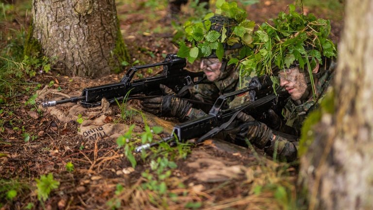 Soldaten der Bundeswehr mit Tarnzweigen auf dem Kopf bei einer Übung im Wald. (Foto: dpa Bildfunk, picture alliance/dpa/Christoph Schmidt (Symbolbild))
