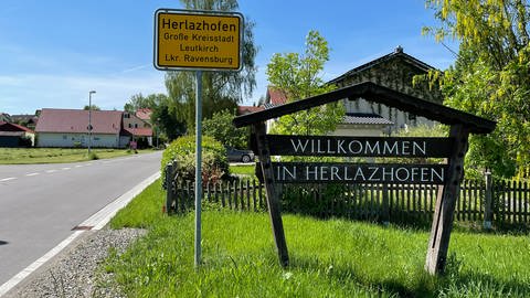 An einem ortseingang steht das gelbe Ortschild mit der Aufschrift Herlazhofen. (Foto: SWR)