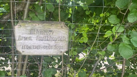 Eine Holztafel erinnert in der Apfelplantage an einen der Verstorbenen.  (Foto: SWR, Tina Löschner)