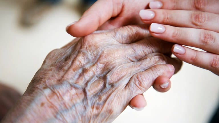 Die Hand einer jungen Frau hält die Hand einer älteren Frau. (Symbolbild) (Foto: dpa Bildfunk, picture alliance/dpa/Christophe Gateau (Symbolbild))
