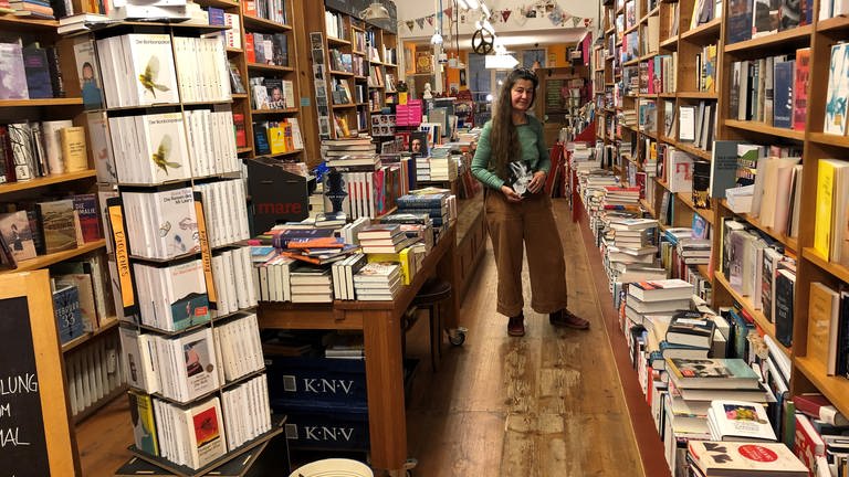 Anna Rahm steht in ihrer Bücherei vor Regalen voller Bücher.