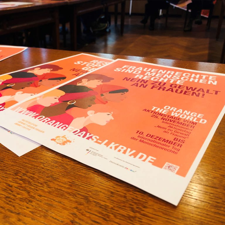 Auf einem Tisch liegen meherere orangefarbene Flyer aufeinander für die Aktionstage Gewalt gegen Frauen. (Foto: SWR, Moritz Kluthe)