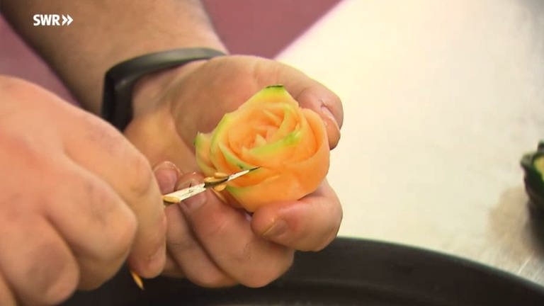 Mit einem kleinen Messer schnitzt Guiseppe Passarelli eine Rose aus einer Melone. (Foto: SWR)