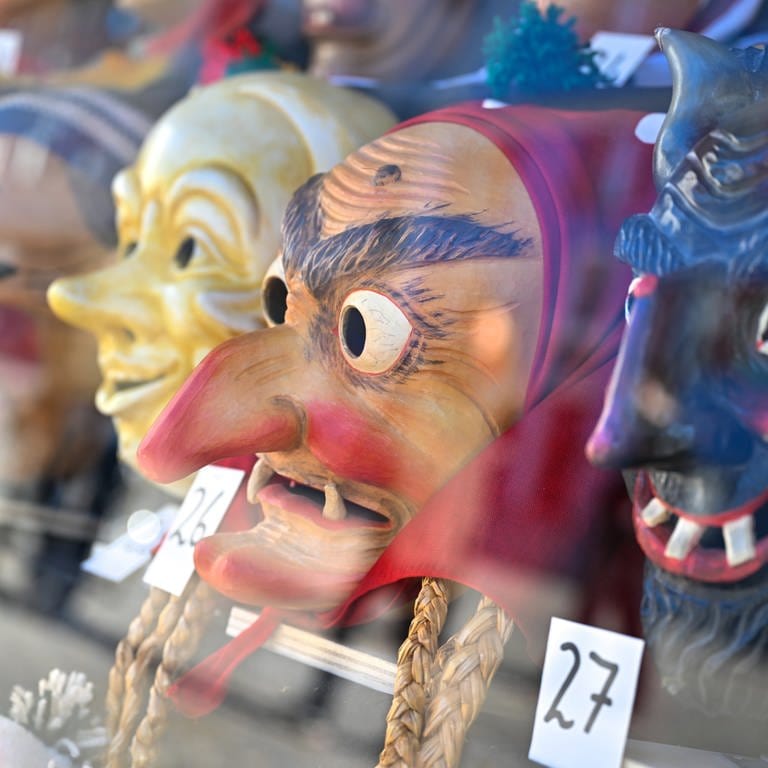 Masken von verschiedenen Narrenzünften liegen in einem Schaufenster in Bad Waldsee.