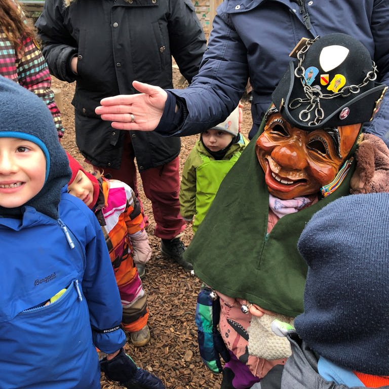 Kinder stehen beisammen. Eines hat eine Holzmaske des Göhrelöchners auf. Die Kinder strahlen. (Foto: SWR, Martin Hattenberger)