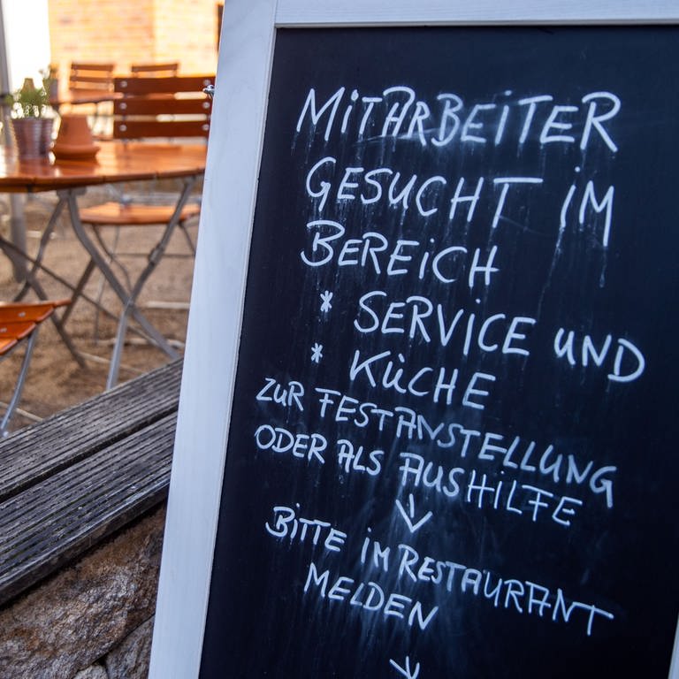 Ein Schild steht vor einer Gaststätte. Darauf steht, dass Mitarbeiter gesucht werden für Service und Küche. (Foto: dpa Bildfunk, picture alliance/dpa/dpa-Zentralbild | Jens Büttner)