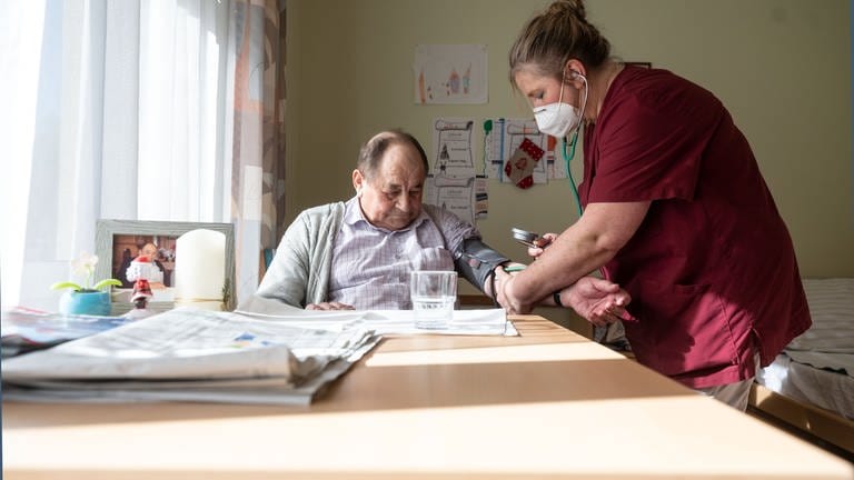 Eine Pflegerin misst einem Mann den Blutdruck  (Foto: dpa Bildfunk, picture alliance/dpa | Marijan Murat (Symbolbild))