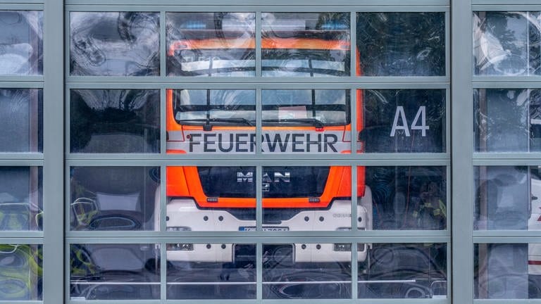 Ein Feuerwehrauto hinter einem Glastor. (Symbolbild) Im Landkreis Konstanz werden Rettungskräfte zukündtig digital alarmiert. (Foto: IMAGO, IMAGO / Jochen Tack)