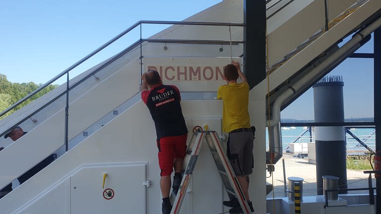 Mitarbeiter bringen den Namen "Richmond" auf der neuen Gasfähre an. (Foto: Pressestelle, Stadtwerke Konstanz)