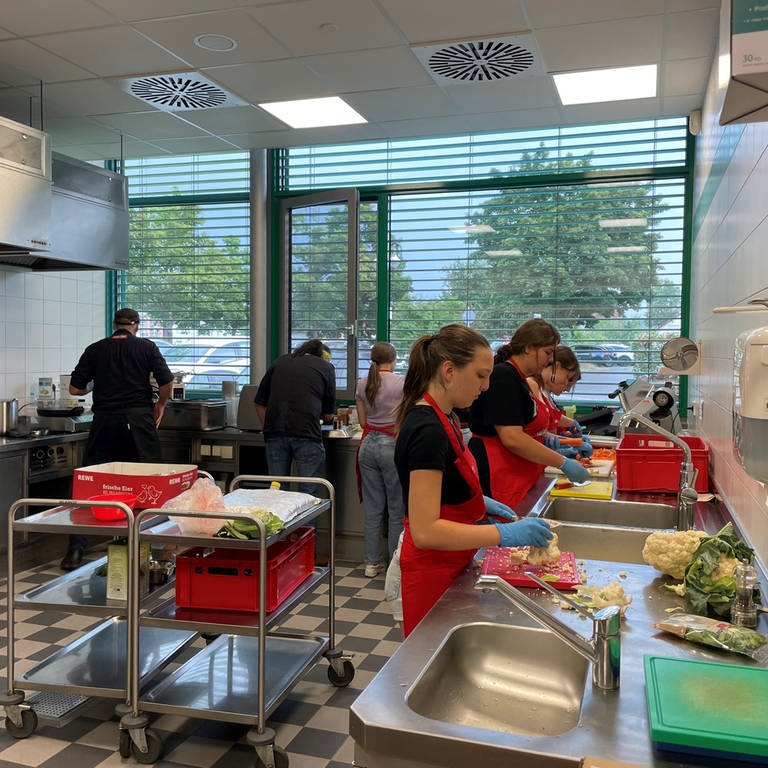 Eine Schülergruppe bereitet zusammen mit Koch Stefan Marquard Essen vor