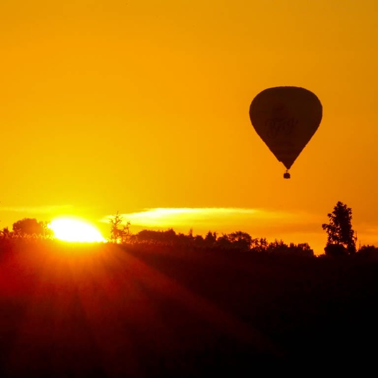 Heißluftballon fährt am Himmel, während die Sonne aufgeht (Symbolfoto). (Foto: dpa Bildfunk, Thomas Warnack)