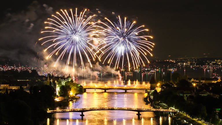 Hunderte Menschen verfolgen in Konstanz, von zwei über den Rhein führenden Brücken aus, das Feuerwerk des Konstanzer Seenachtfestes.