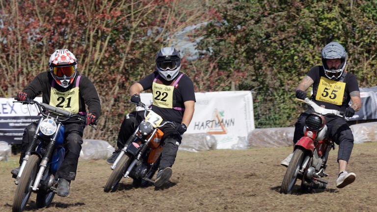 Drei Motorradfahrer fahren auf einer holpringen Rennstrecke mit Simson-Motorrädern