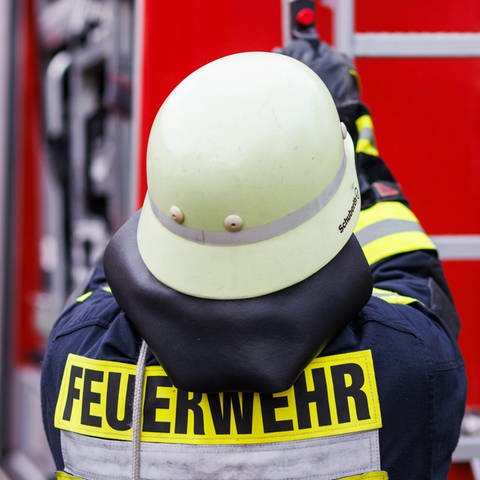 Ein Feuerwehrmann mit Helm von hinten.