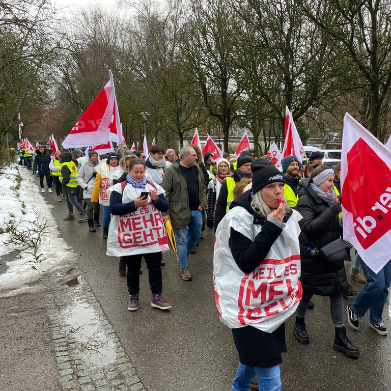 Teilnehmerinnen und Teilnehmer eines Warnstreik-Protestzugs ziehen mit ver.di-Flaggen durch Ravensburg. (Foto: SWR, Bernhard Hentschel)