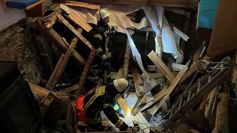 Feuerwehrleute stehen auf einem eingebrochenen Boden. In Laupheim ist in der Nacht auf Sonntag der Boden eines leerstehenden Hauses durchgebrochen. 