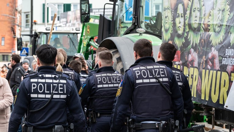 Polizisten gehen während einer Demonstration vor Beginn des politischen Aschermittwochs der baden-württembergischen Grünen vor der Stadthalle in Biberach an der Riß. (Foto: dpa Bildfunk, picture alliance/dpa | Silas Stein)