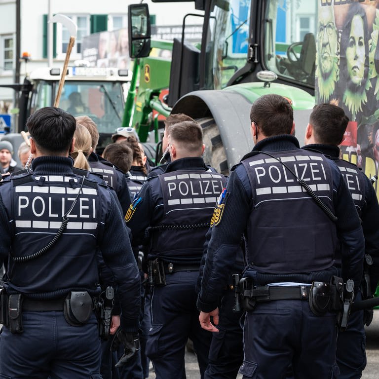 Polizisten gehen während einer Demonstration vor Beginn des politischen Aschermittwochs der baden-württembergischen Grünen vor der Stadthalle in Biberach an der Riß. (Foto: dpa Bildfunk, picture alliance/dpa | Silas Stein)