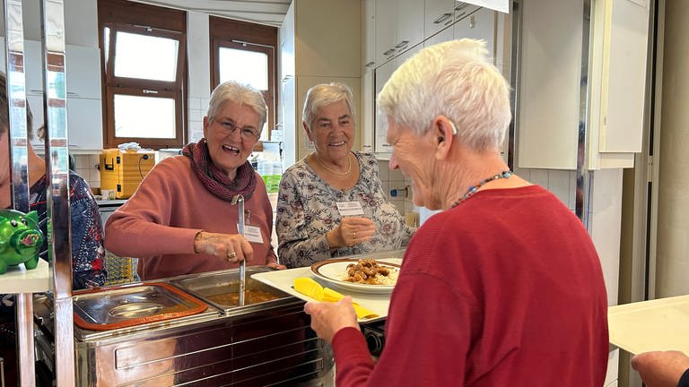 Zwei Frauen geben bei der Friedrichshafener Vesperkirche Essen aus. (Foto: SWR, Nadine Ghiba)