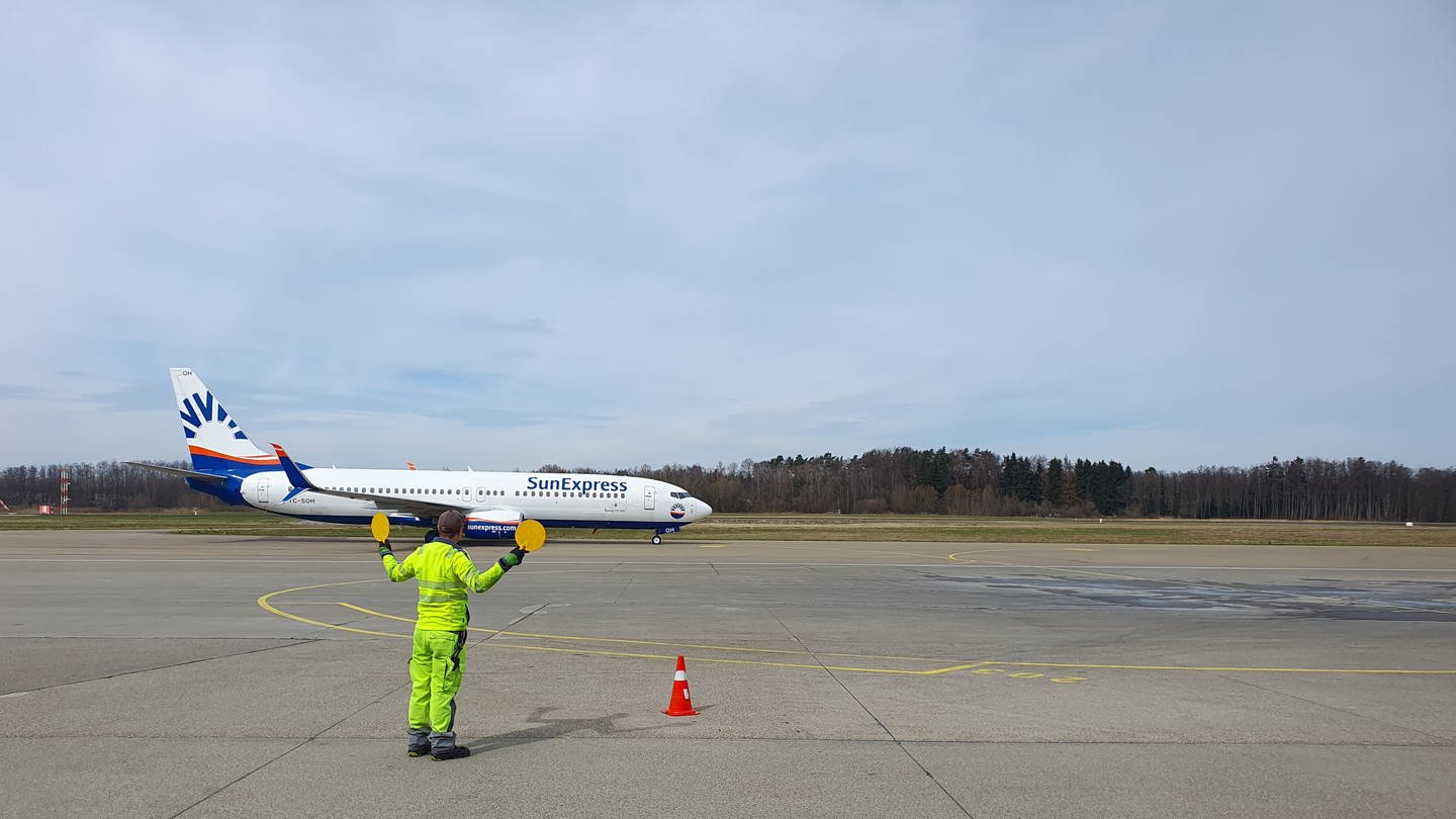 Ein Marshaller weist ein Flugzeug auf dem Flughafen Friedrichshafen ein (Foto: SWR, Friederike Fiehler)