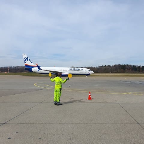 Ein Marshaller weist ein Flugzeug auf dem Flughafen Friedrichshafen ein