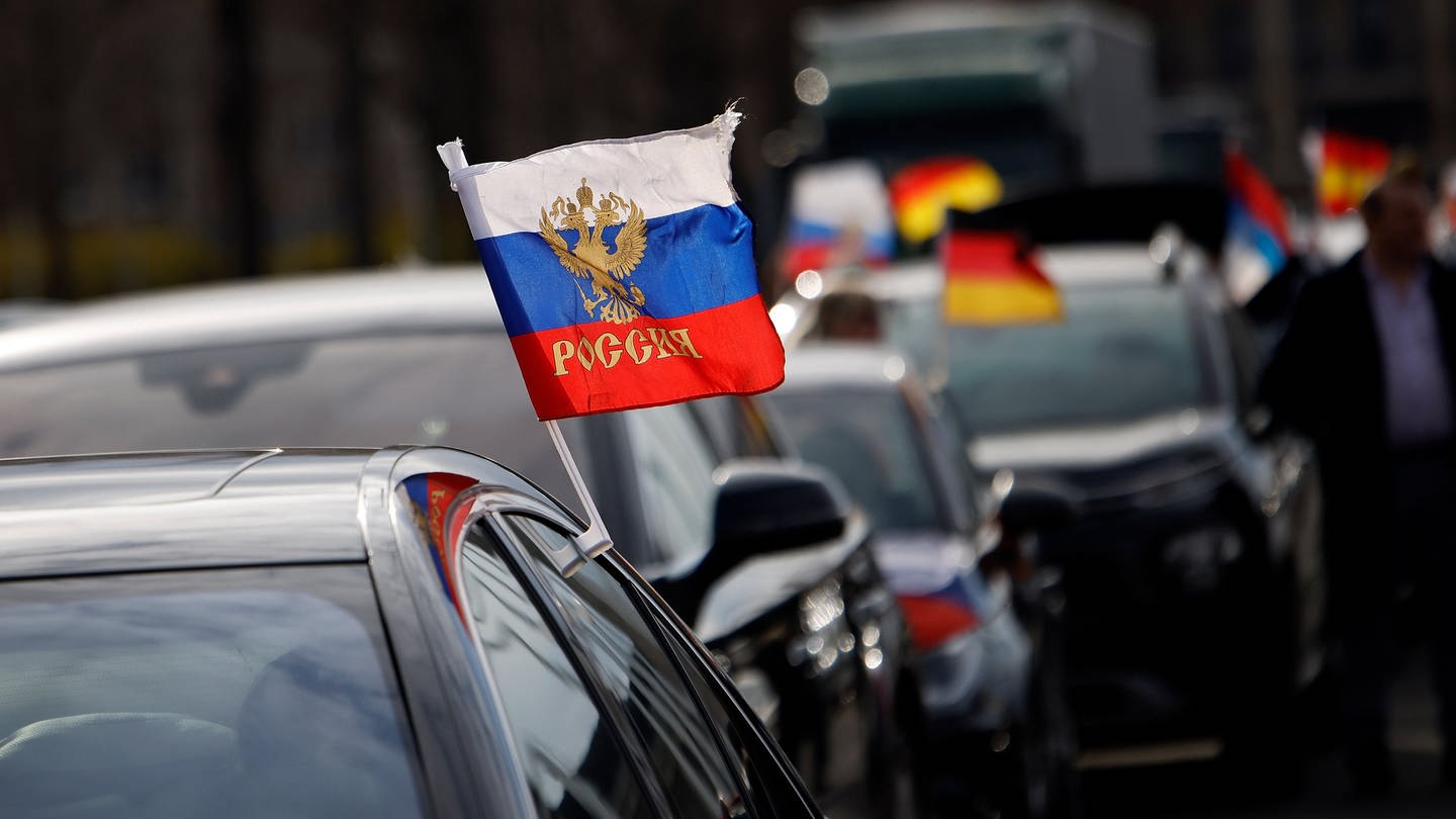 Flaggen mit den russischen Nationalfarben und dem russischen Staatswappen wehen an einem Autoan einem Autokorso