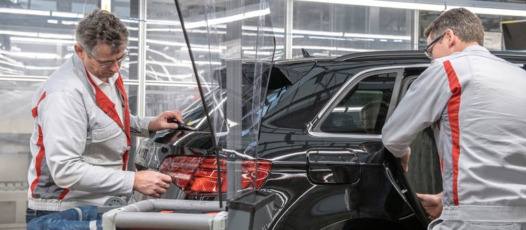 Zwei Männer arbeiten in eienr Halle an einem Auto (Foto: Pressestelle, Audi AG)