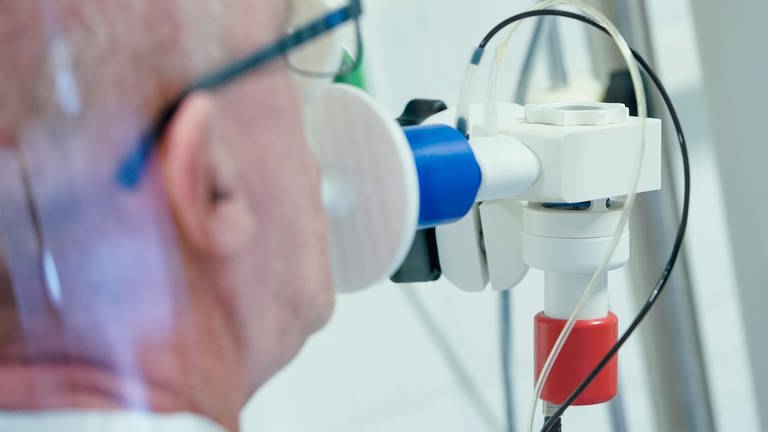 Ein von einer Corona-Erkrankung genesener Patient bekommt in einer Lungentest-Kabine in einer Rehaklinik die Lungenfunktion gemessen (Foto: dpa Bildfunk, picture alliance/dpa | Uwe Anspach)