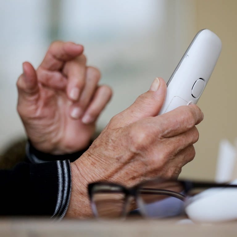 Eine Hand hält ein Telefon. Symbolbild Trickbetrüger. (Foto: dpa Bildfunk, picture alliance/dpa | Roland Weihrauch)