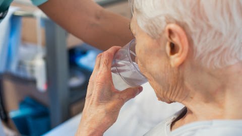  Eine alte Frau trinkt aus einem Glas Wasser (Symbolbild): Vor allem ältere Menschen leiden unter der Hitze (Foto: dpa Bildfunk, picture alliance/dpa | Jana Bauch)