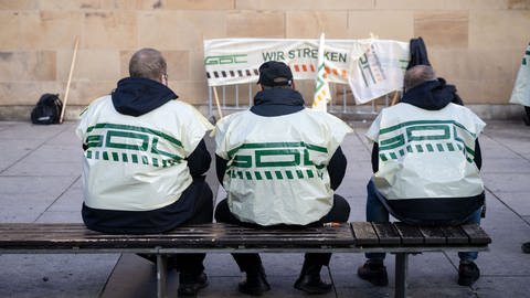 Teilnehmer eines Warnstreiks der Gewerkschaft Deutscher Lokomotivführer (GDL) sitzen vor dem Heilbronner Hauptbahnhof auf einer Bank (Foto: dpa Bildfunk, Picture Alliance)
