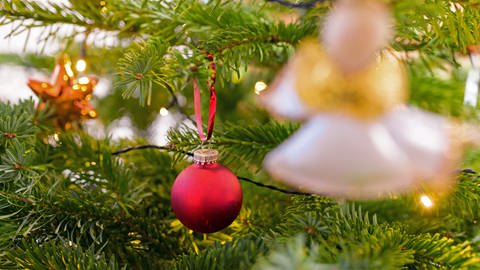 Weihnachtsschmuck hängt an einem Christbaum. Früher wurde unterm Weihnachtsbaum Lieder wie "O Tannenbaum" angestimmt (Foto: dpa Bildfunk, picture alliance/dpa | Jonas Walzberg)